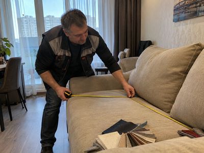 Мастер-замерщик снимает размеры дивана